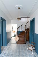 Classic hallway with patterned blue and white floor and wooden staircase