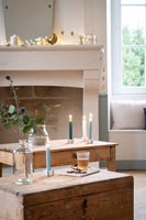 Lit candles on wooden furniture and fairy lights over mantelpiece 