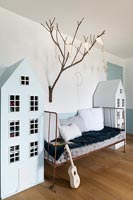 Matching dolls houses flanking daybed in childrens room 