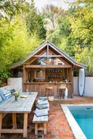 Wooden structure used as outdoor bar next to swimming pool 