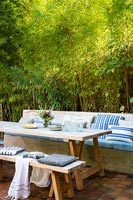 Large outdoor dining area with built-in bench seat covered in cushions 