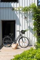 Bicycle and shopping basket by front door of modern country house 