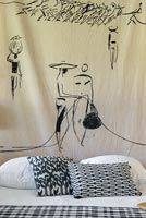 Painted wall hanging over black and white bed 