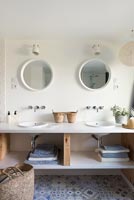Twin sinks in modern bathroom with patterned blue and white floor tiles 
