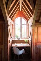 Dressing table in small alcove next to window of wooden country bedroom 