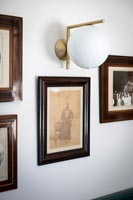 Detail of framed paintings and wall light 