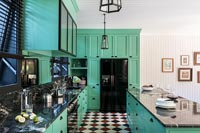 Bright green modern kitchen with red, white and black checkerboard flooring 