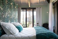 Open French window in modern country bedroom with painted feature wall 