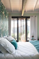 Open French windows in modern bedroom with painted headboard 