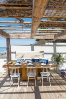 Outdoor dining area on decking overlooking beach 