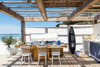Surfboard in outdoor kitchen-diner overlooking sea 