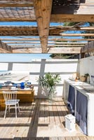 Outdoor kitchen and dining area under wooden pergola 