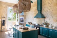 Modern country kitchen with teal painted woodwork and exposed stone walls 