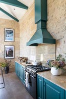 Modern country kitchen with teal painted woodwork and exposed stone walls 