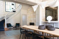 Modern dining room with exposed stone walls and staircase 