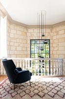 Black armchair on upstairs landing with view of stained glass window 