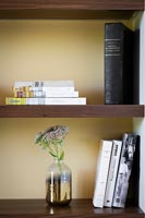 Bookshelf with books and vase of flowers 