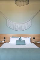 Aqua blue painted modern bedroom with white fabric tassel wall hanging 