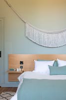 Aqua blue painted modern bedroom with white fabric tassel wall hanging 
