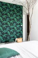 Green wallpapered feature wall and bare tree branch ornament in modern bedroom