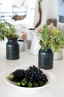 Black grapes and aubergines on white plate in modern kitchen 