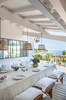 White outdoor dining room with view to sea beyond 