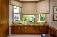 Built-in window seat with storage and gold cushions 