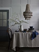 Bead chandelier over table with tablecloth in muted tones 
