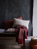 Red and white soft furnishings against black fabric wall hanging  