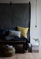 Black, grey and yellow soft furnishings against black fabric wall hanging  