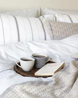 Book and hot drinks on tray in bedroom 