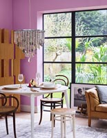 Modern dining room with pink walls and crystal chandelier