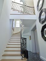 Hallway and staircase with display of mirrors on wall and marble floor 