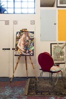 Easel with colourful modern artwork in eclectic living room 