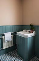 White sink unit in blue painted wood paneled bathroom 
