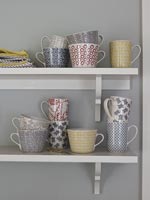 Variety of patterned mugs on shelves 