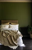 Cream bedding in dark green painted bedroom 