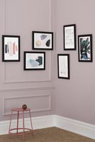Framed paintings on dusky pink painted wall 