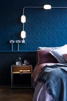 Pink bedding and dark blue painted brickwork in modern bedroom 