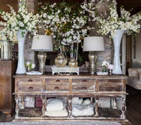 White flowers displayed in large vases on distressed wooden sideboard 