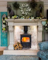 Lit wood burner in large fireplace surrounded by floral decorations 