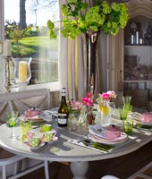 Modern dining room laid for lunch wtih pink and green accessories 