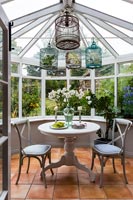 Decorative bird cages above small cafe table and chairs in conservatory