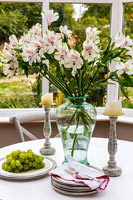 Vase of flowers on small cafe table in conservatory