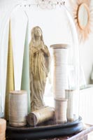 Cotton reels, candles and gold statuette under glass dome 