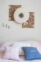 Modern bedroom with fabric flower and pictures above bed 