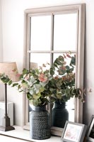 Vase of leaves and foliage on radiator cover with mirror 