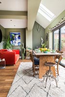 Green painted walls and bright orange sofa in modern dining room 
