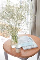 Cut wildflowers in vase on side table with books 
