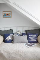 Nautical themed cushions on bed in country bedroom 